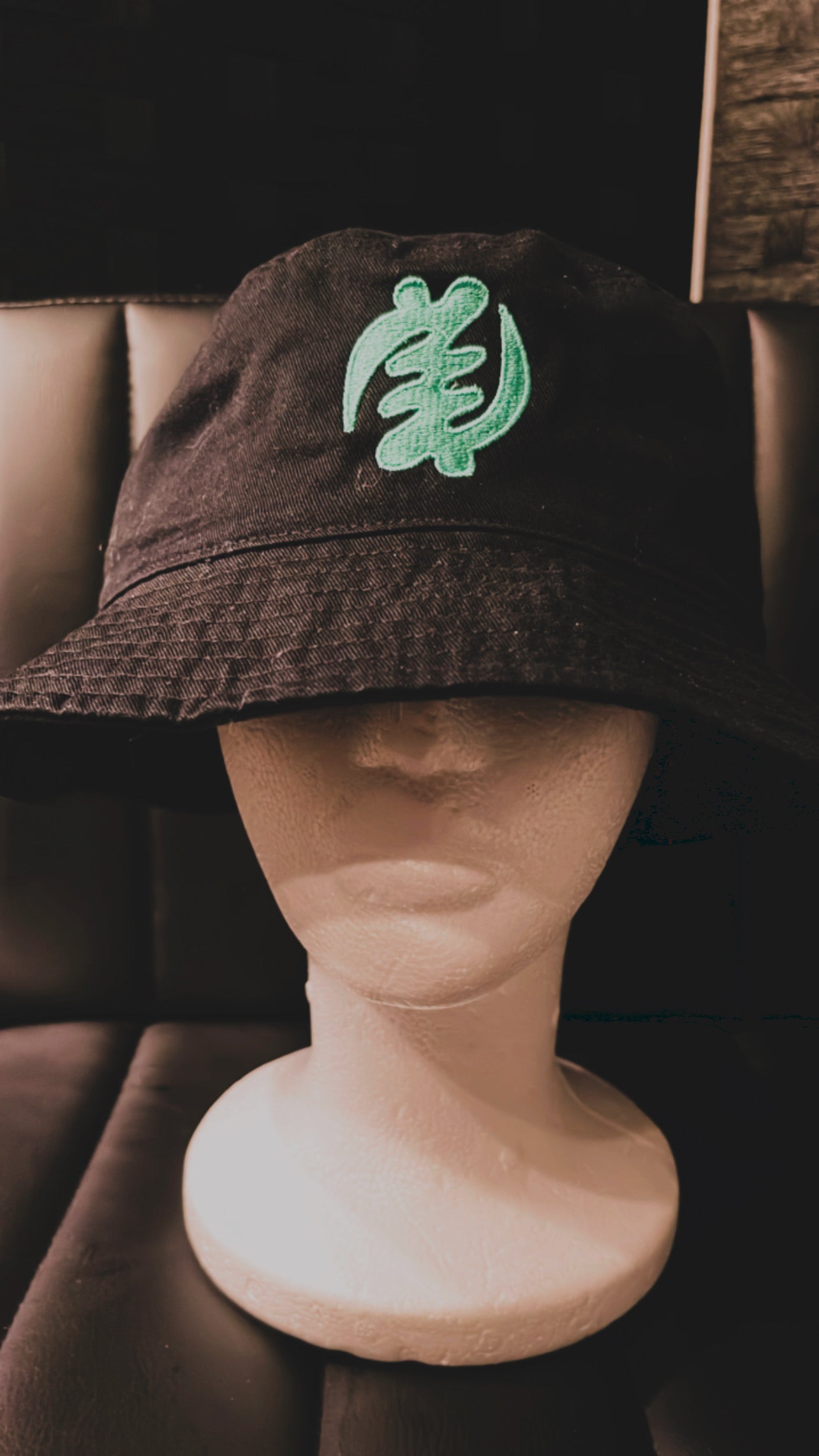Get a stylish and unique look with our black bucket hat featuring the iconic Gye Nyame symbol in mint blue. Handmade in Ghana, this hat is perfect for any occasion. Shop now and add a touch of African culture to your wardrobe!